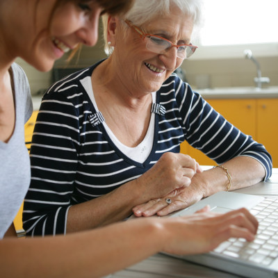 Retraitée souriante devant un ordinateur près d'une femme